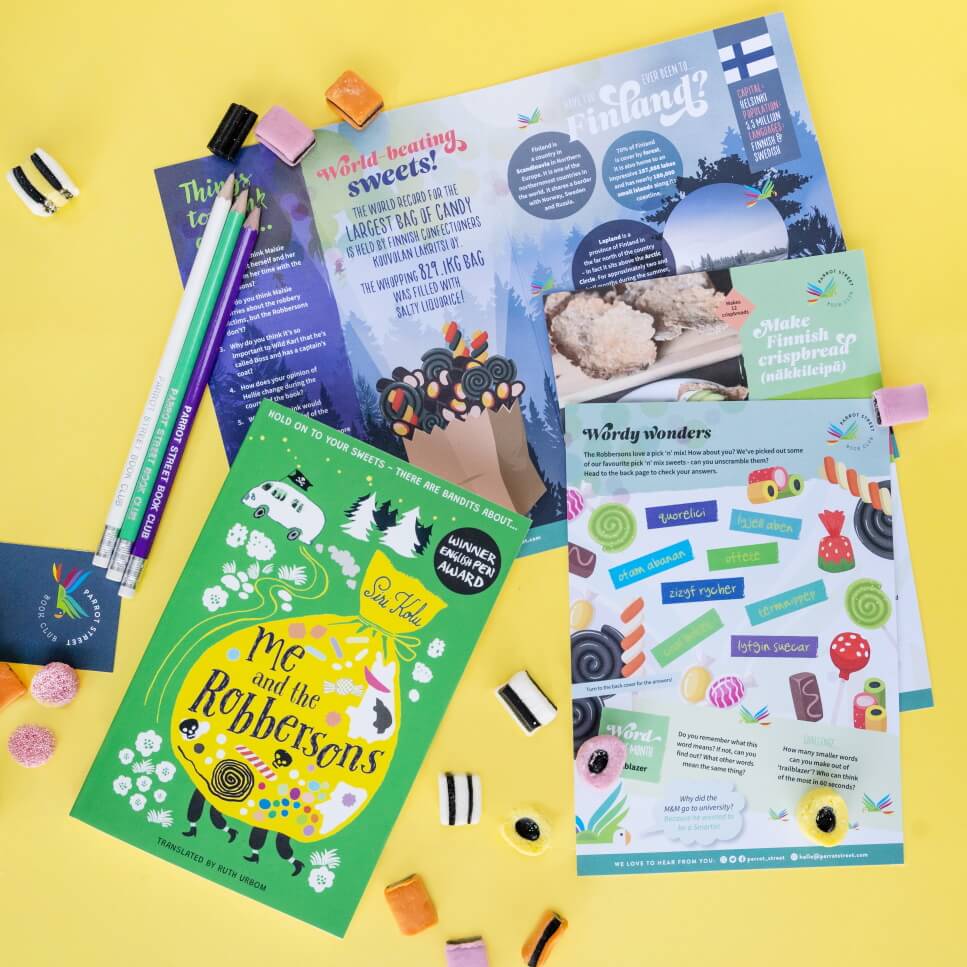 Image shows a colourful children's book called Me and the Robbersons, laying on top of a fact sheet about sweets. Alongside this is an activity sheet. Surrounding them are various Liqourice Allsorts, and to the top left are three pencils which say "Parrot Street Book Club" on them.